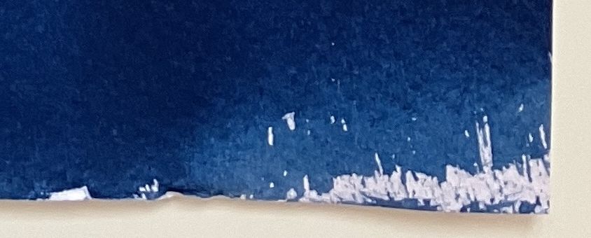 A corner of a blue sheet of paper, with irregular shapes of white.